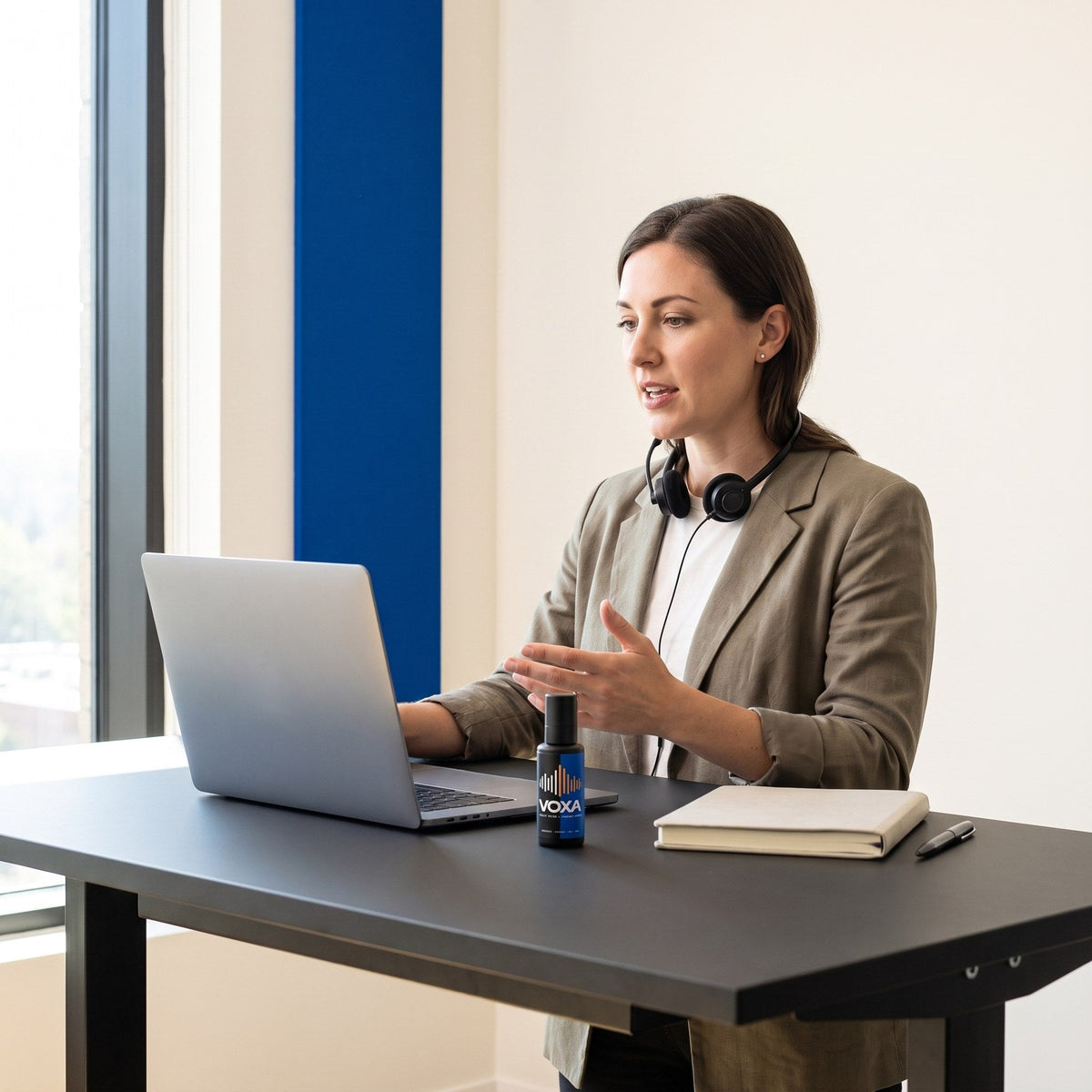 VOXA on a standing desk beside a laptop during a video call