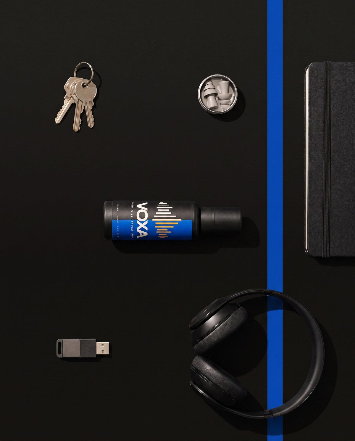 Flat lay of VOXA with keys, earplugs, headphones and a notebook